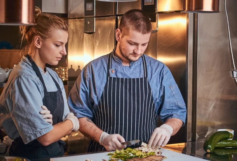 male-chef-with-assistant-standing-in-a-kitchen-pre-PCVW5CR-1.jpg